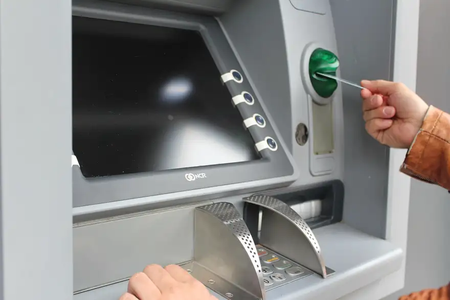 A person inserting a card into a self-service kiosk, similar in layout to the crypto kiosks found in Seattle grocery stores
