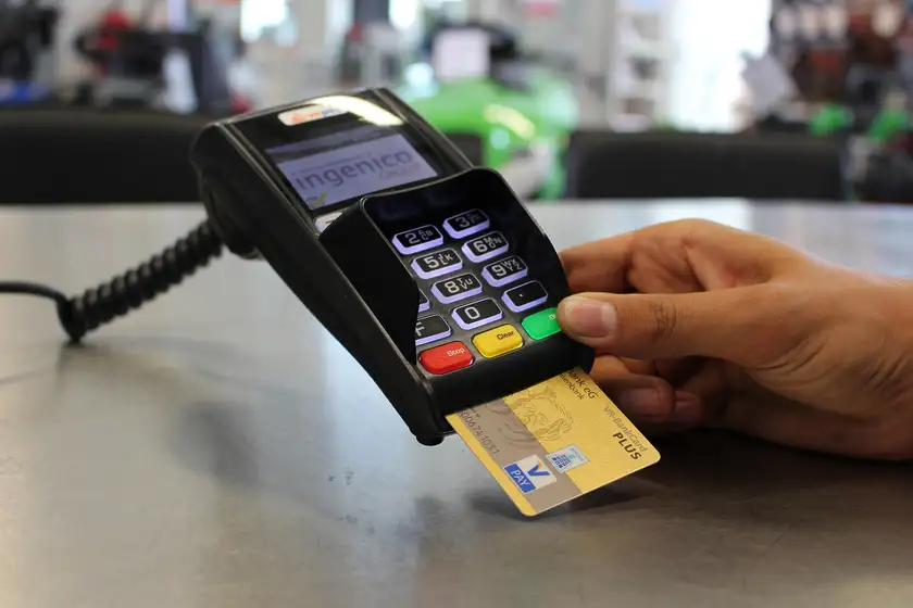 A hand inserting a bank card into a card payment terminal on a retail counter