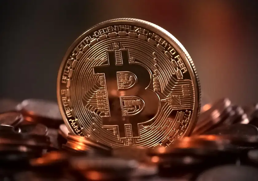 A single bitcoin token photographed in close-up on a bed of other coins